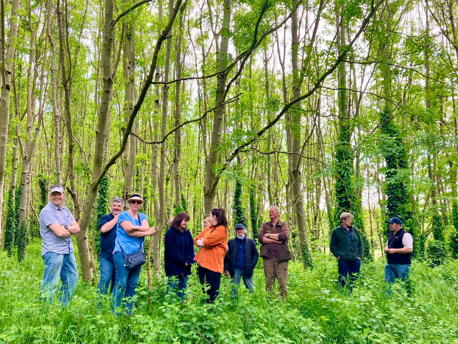 A group of farmers listing to a biodiversity talk in a forest. 